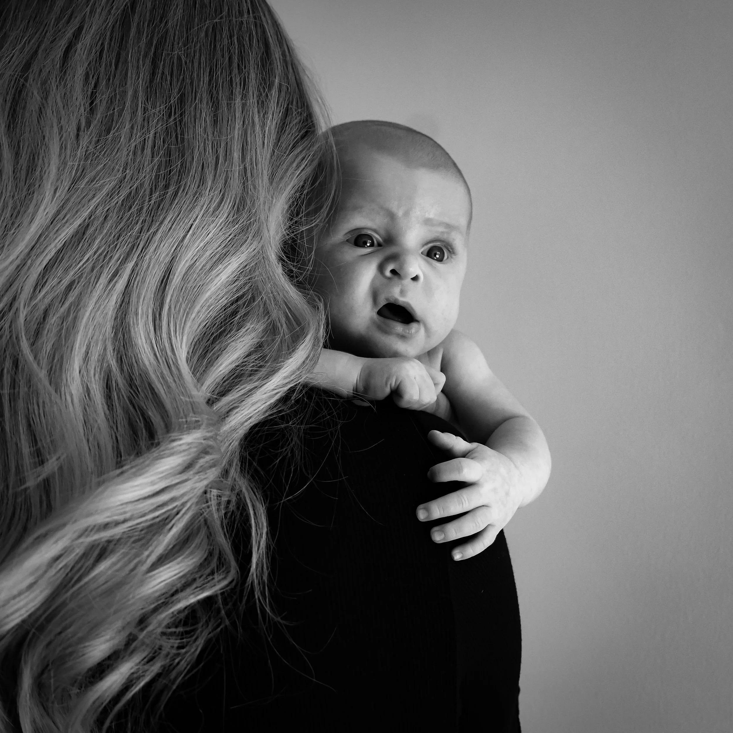 Natürliche Newbornfotografie in Hannover. Das Baby wird liebevoll auf der Schulter gehalten und entdeckt aufmerksam seine Umgebung. Die Aufnahme zeigt Nähe, Geborgenheit und die ersten gemeinsamen Momente als Familie.