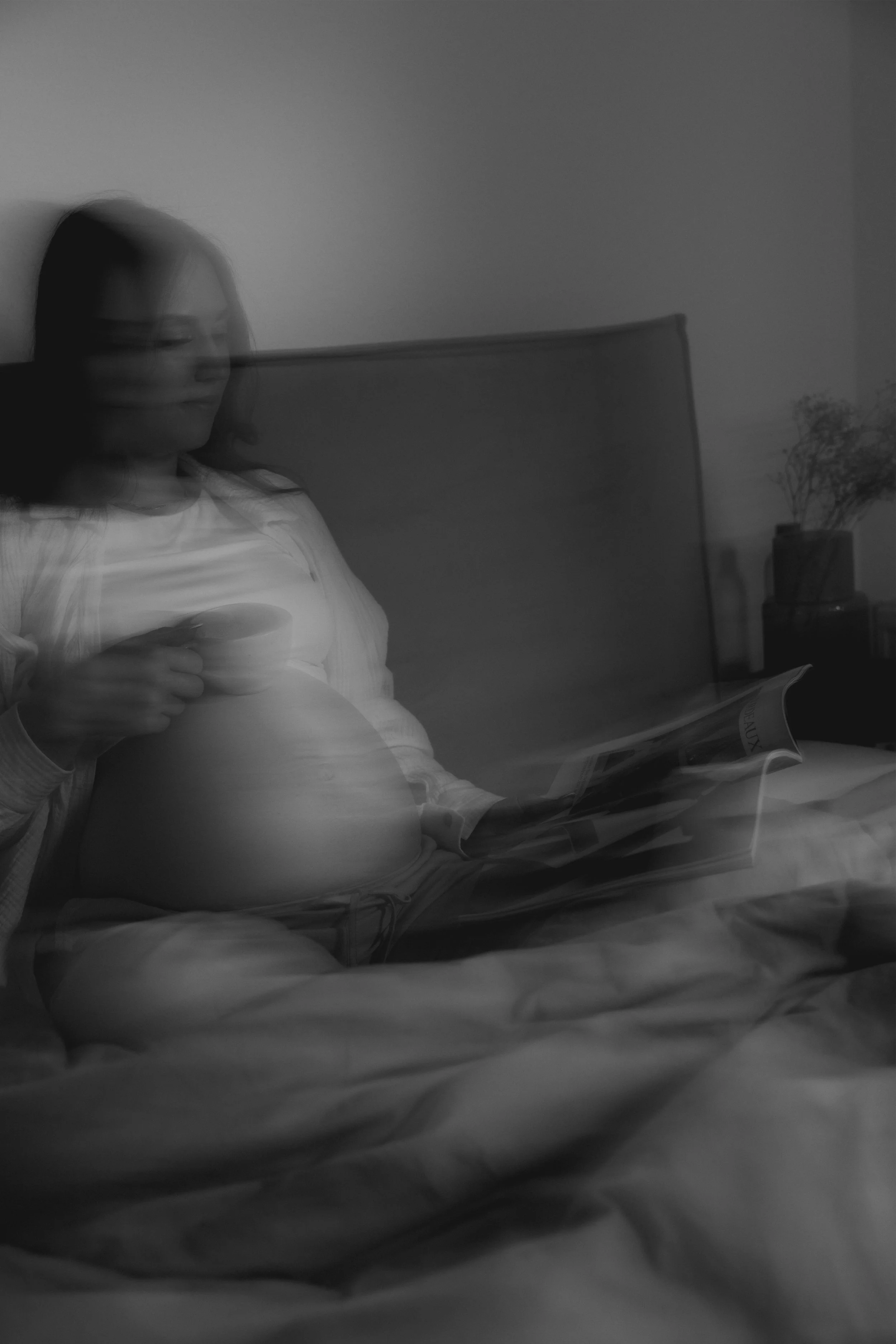 Eine Frau sitzt entspannt auf einem Sofa, liest ein Magazin und trinkt aus einer Tasse, in einem gemütlichen Raum.