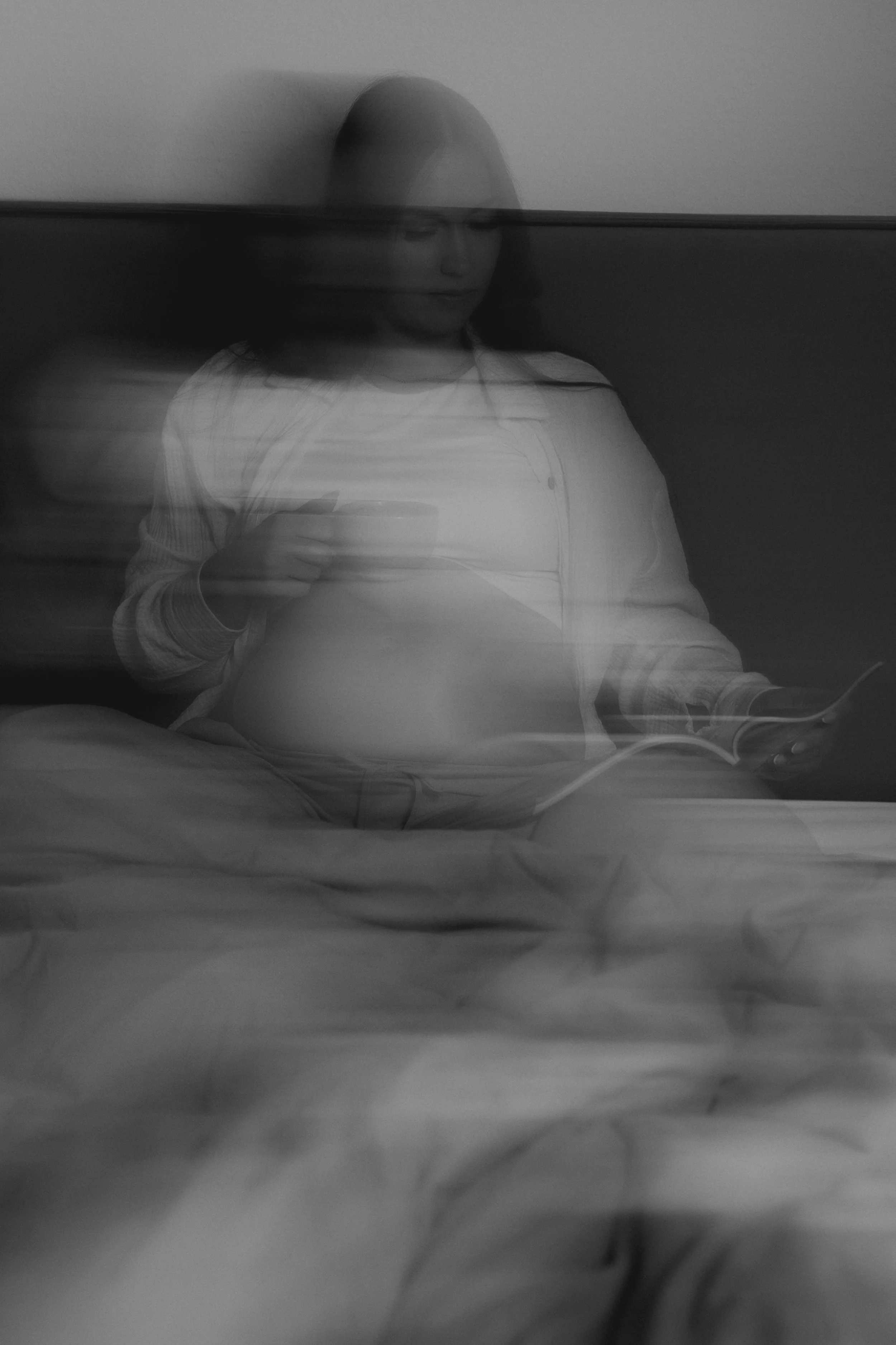 Frau im Wasser, halb unter Wasser, sitzend auf einem Bett, hält ein Handy, in Schwarz-Weiß-Ästhetik, surreal