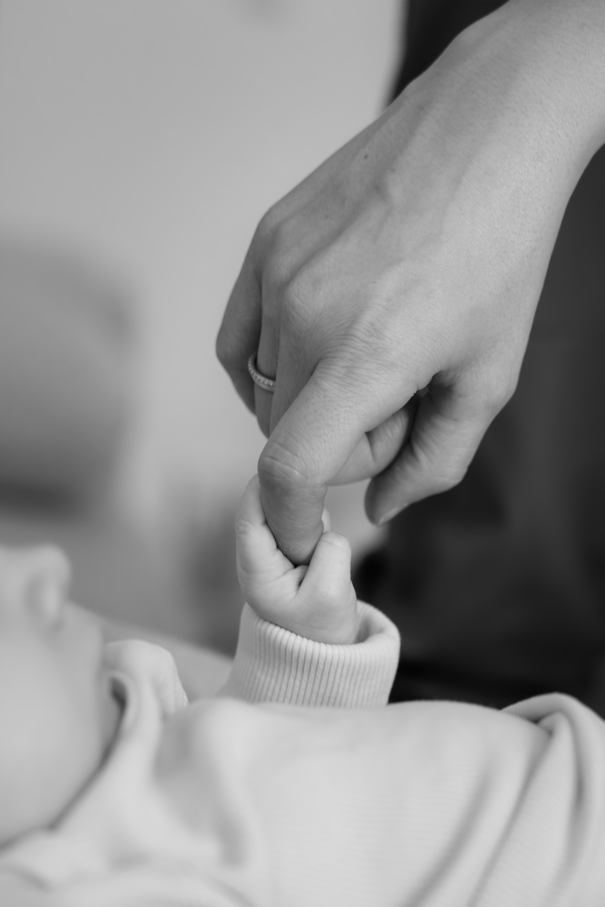 Baby hält während eines natürlichen Newbornshootings in Hannover den Finger eines Elternteils fest.