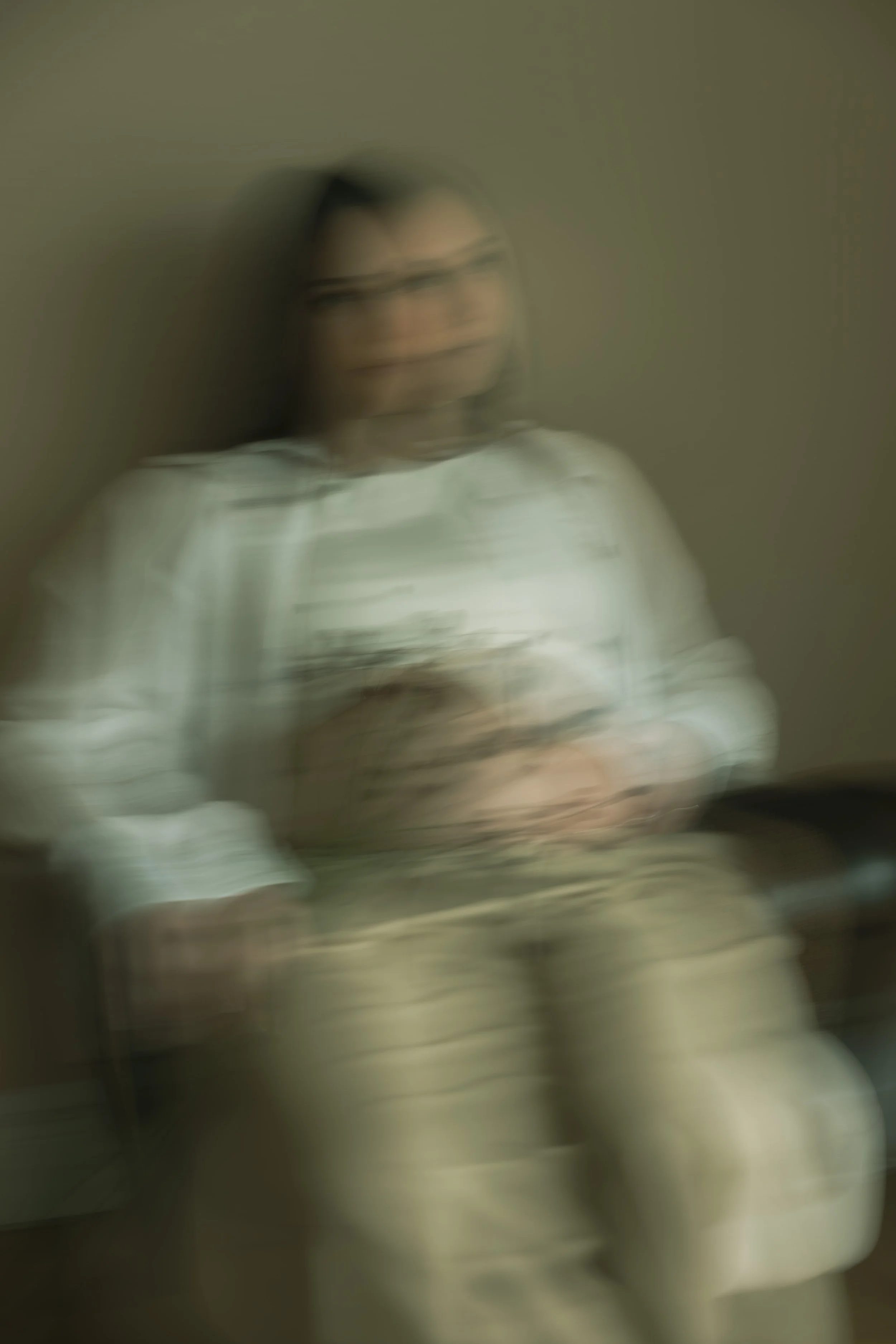 Eine Person mit dunklen Haaren und Brille sitzt an einem Tisch und schaut auf einen Laptop, alles ist absichtlich unscharf und verschwommen.