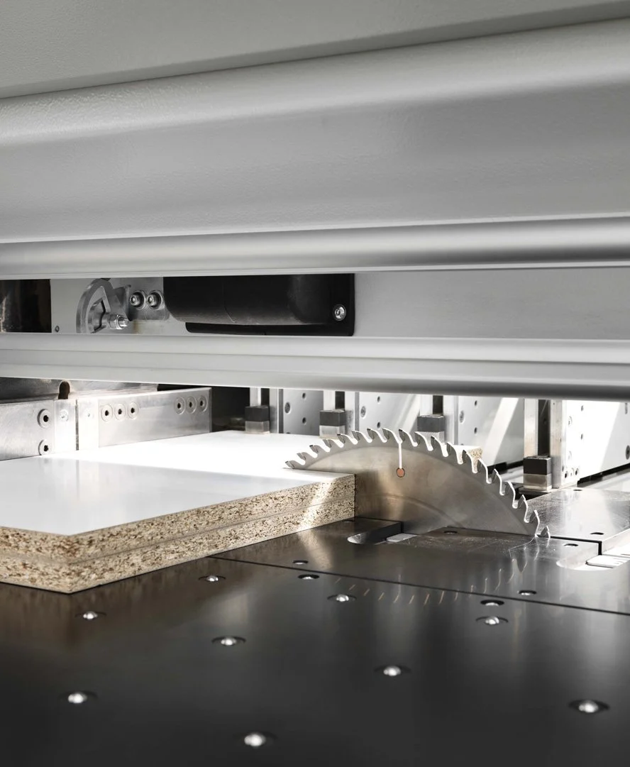 Close-up of a circular saw industrial machine cutting a piece of particle board.