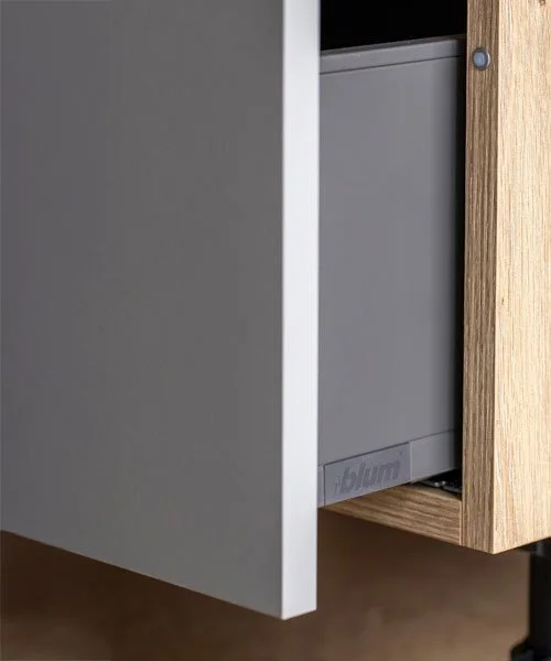 Close-up of a gray appliance, possibly a dishwasher or refrigerator, installed next to a wooden cabinet.