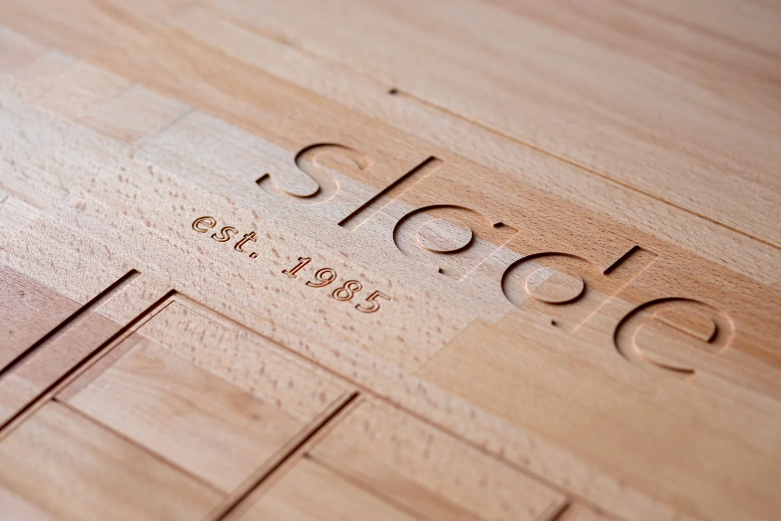 Close-up view of a wooden surface with laser-engraved slade kitchens logo