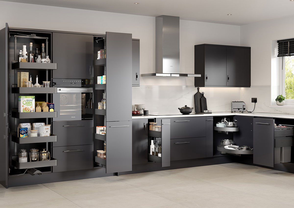 Modern kitchen with dark gray cabinets, open cabinet doors revealing pantry items, a marble backsplash, and stainless steel appliances, with a window on the right side letting in natural light.