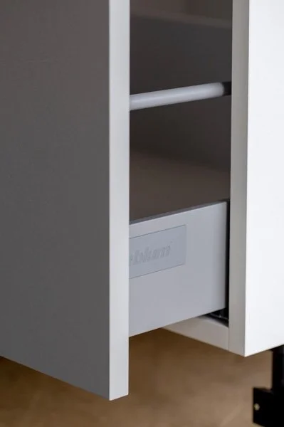 Close-up of a white furniture piece with open shelves and a drawer at the bottom.