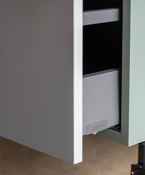 Part of a kitchen cabinet with an open drawer and a pull-out trash bin.