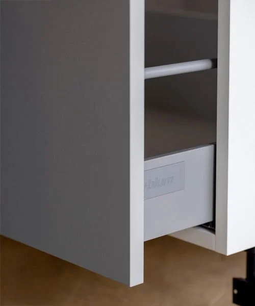 Close-up of a white cabinet drawer partially pulled out, showing the inside with a cabinet organizer and a visible label.