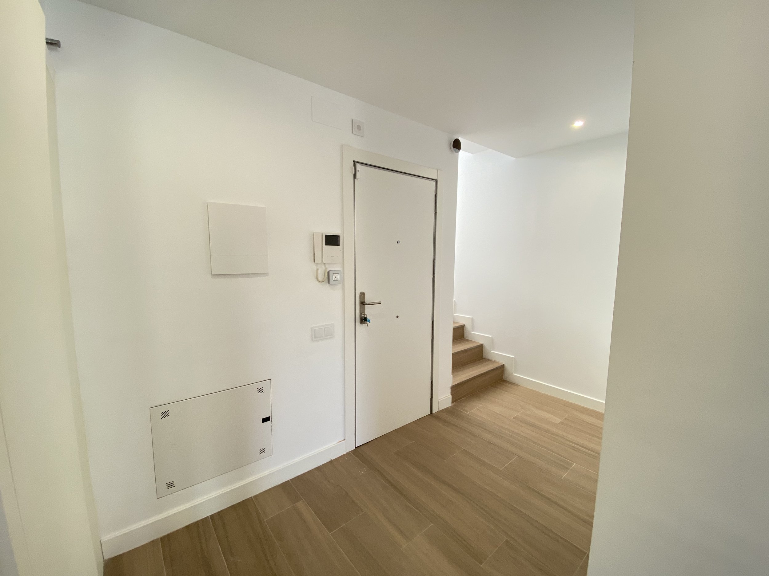 Vestíbulo con puerta de entrada, escaleras y suelo de madera