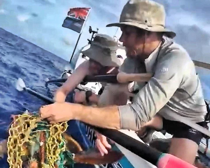 Two ocean rowers rescue a turtle that's stuck in a net.