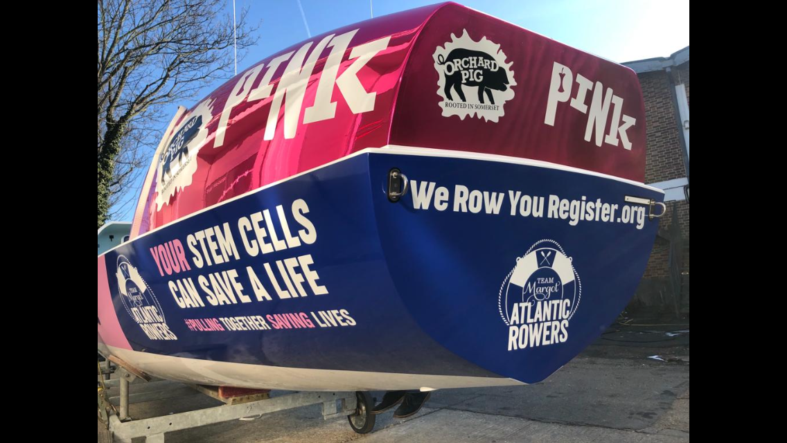 Team Margot's Ocean rowing boat with Orchard Pig and Atlantic Rowing Team, with messages about stem cell research and rowing registration.