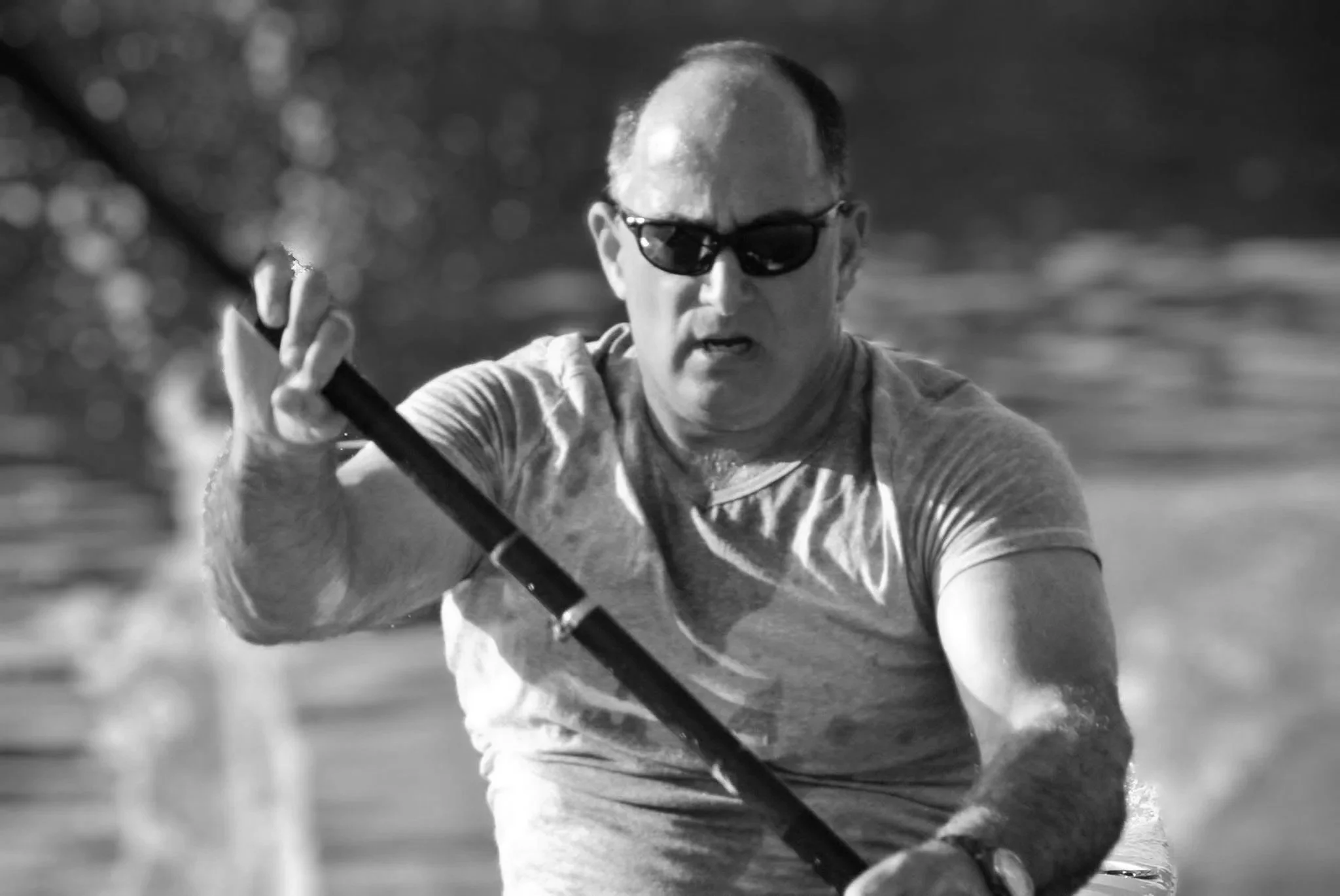 Black and white photo of Guy Dresser wearing sunglasses kayaking.