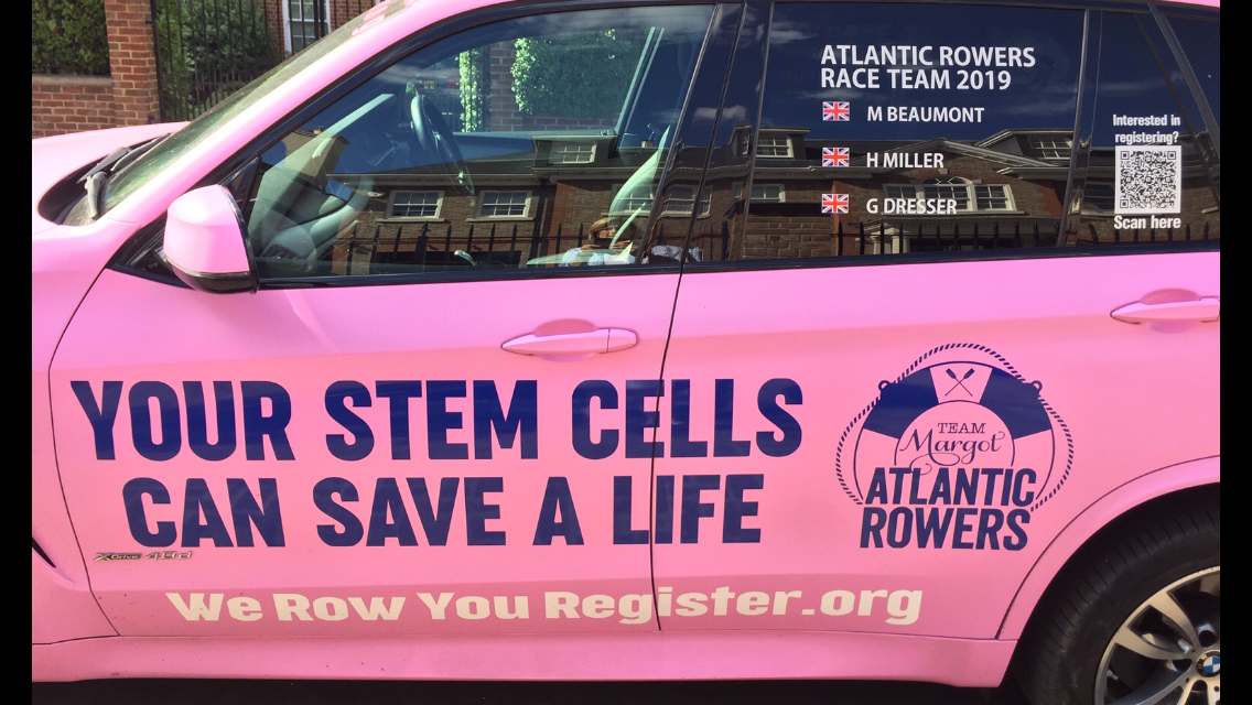Pink car displaying message about stem cells saving lives, with logos for team Margot and Atlantic Rowers, and a QR code for registration.