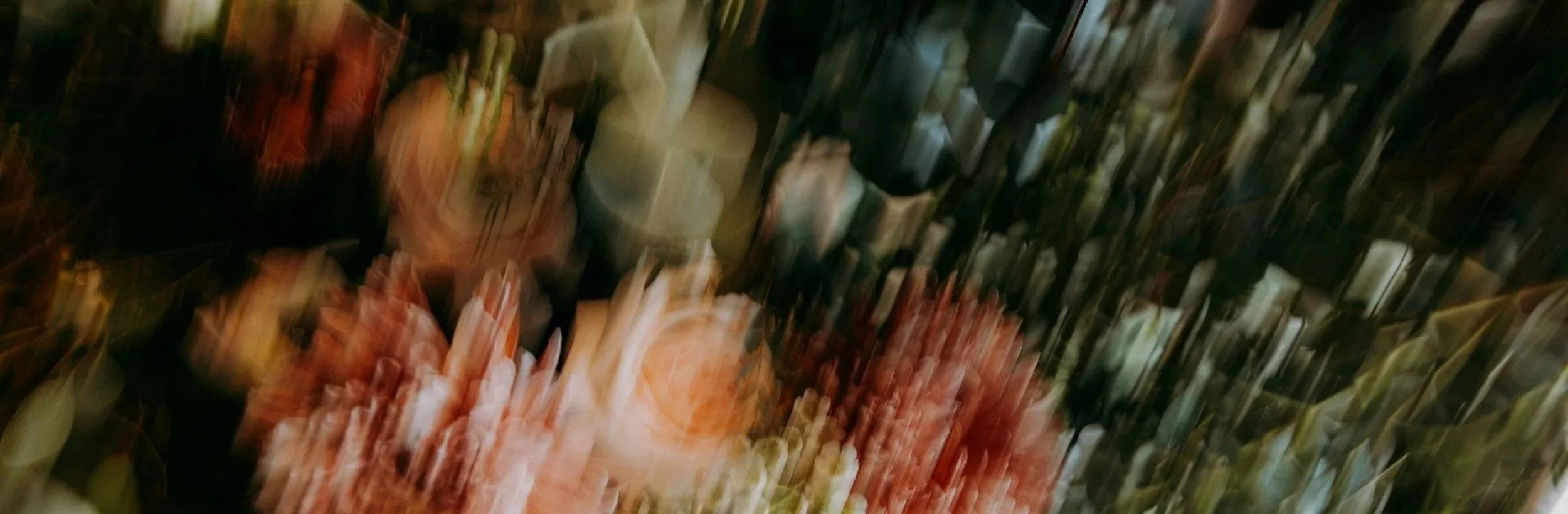 Abstract, blurry image with streaks of various colors, including green, orange, black, beige, and white, creating an indistinct pattern.