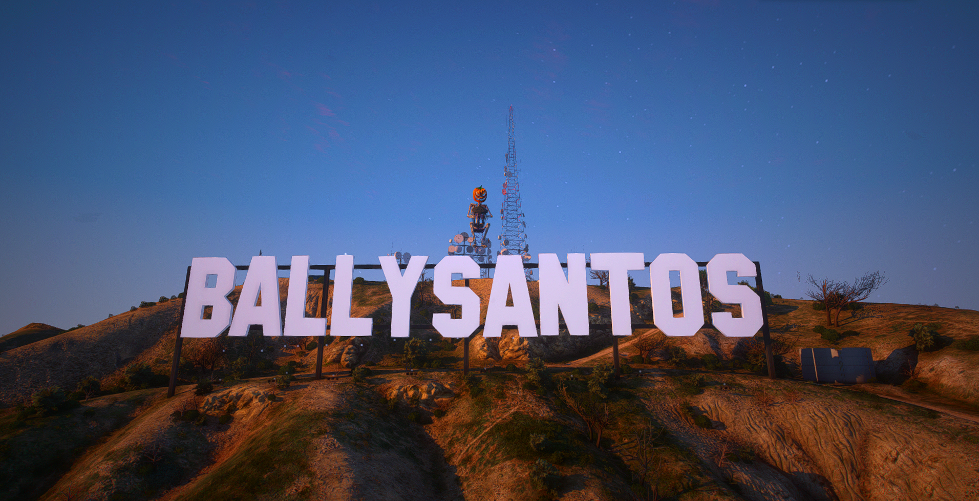 Nighttime view of the Hollywood sign reading "Ballysantos" on a hillside, with trees, rocks, and a star-filled sky in the background, and a Halloween jack-o'-lantern decoration atop a tower.