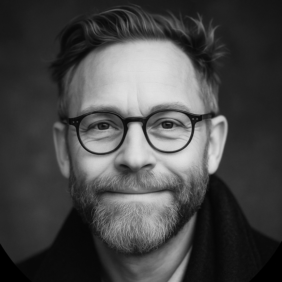 Black and white portrait of a smiling man with glasses and a beard.