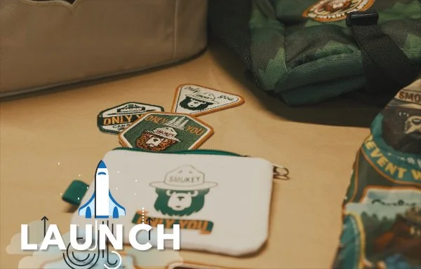 Launch text with smokey bear bag and patches