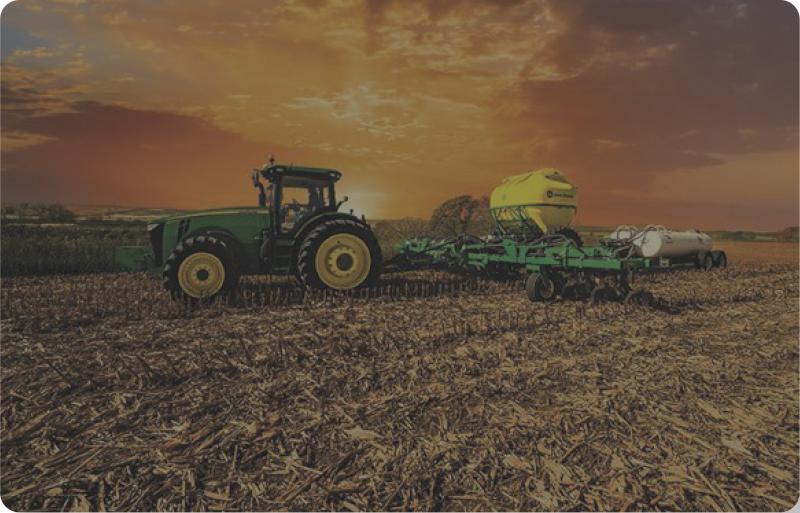 John Deere tractor plowing a field at sunrise