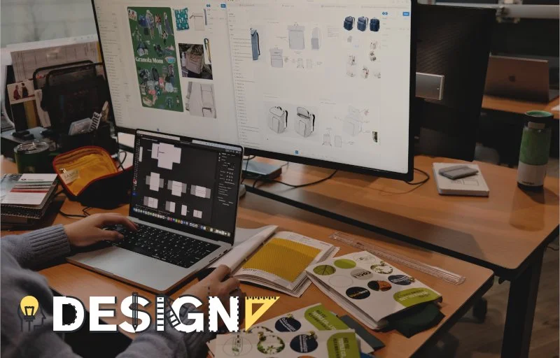 Design text with person at desk with laptop, monitor, and brochures on the desk