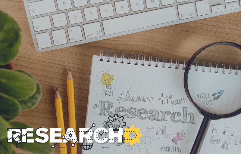 Research text with computer keyboard, magnifying glass, sketch book, and pencils