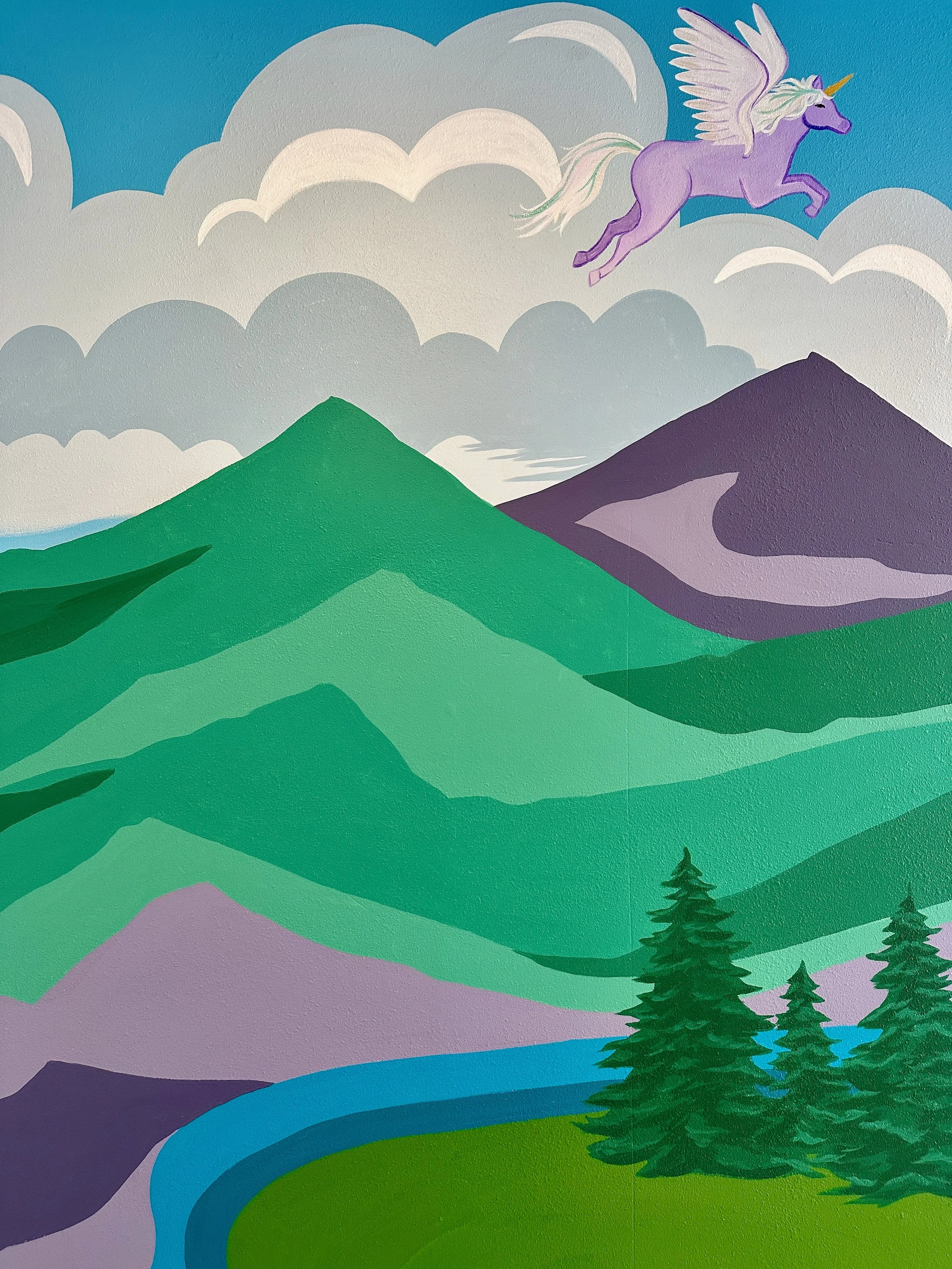 Colorful mural of mountains, pine trees, a river, clouds, and a flying purple unicorn with a rainbow mane and horn.