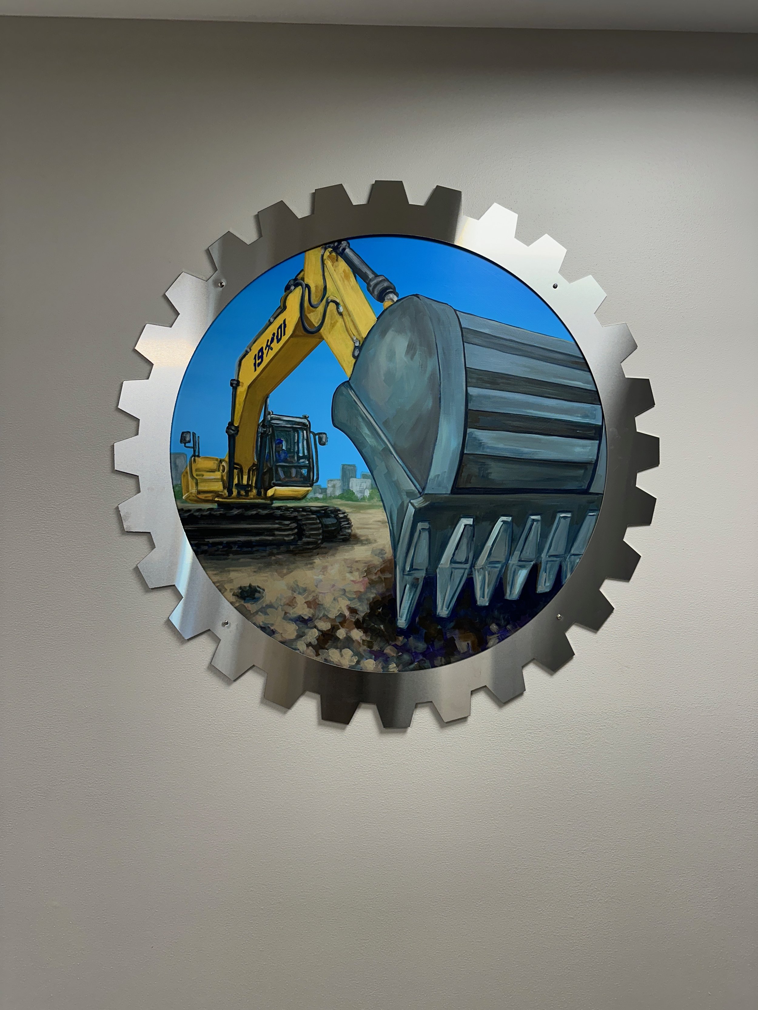 Painting of construction equipment, specifically a yellow excavator and a large scoop, with a city skyline in the background, framed within a gear-shaped metallic border.