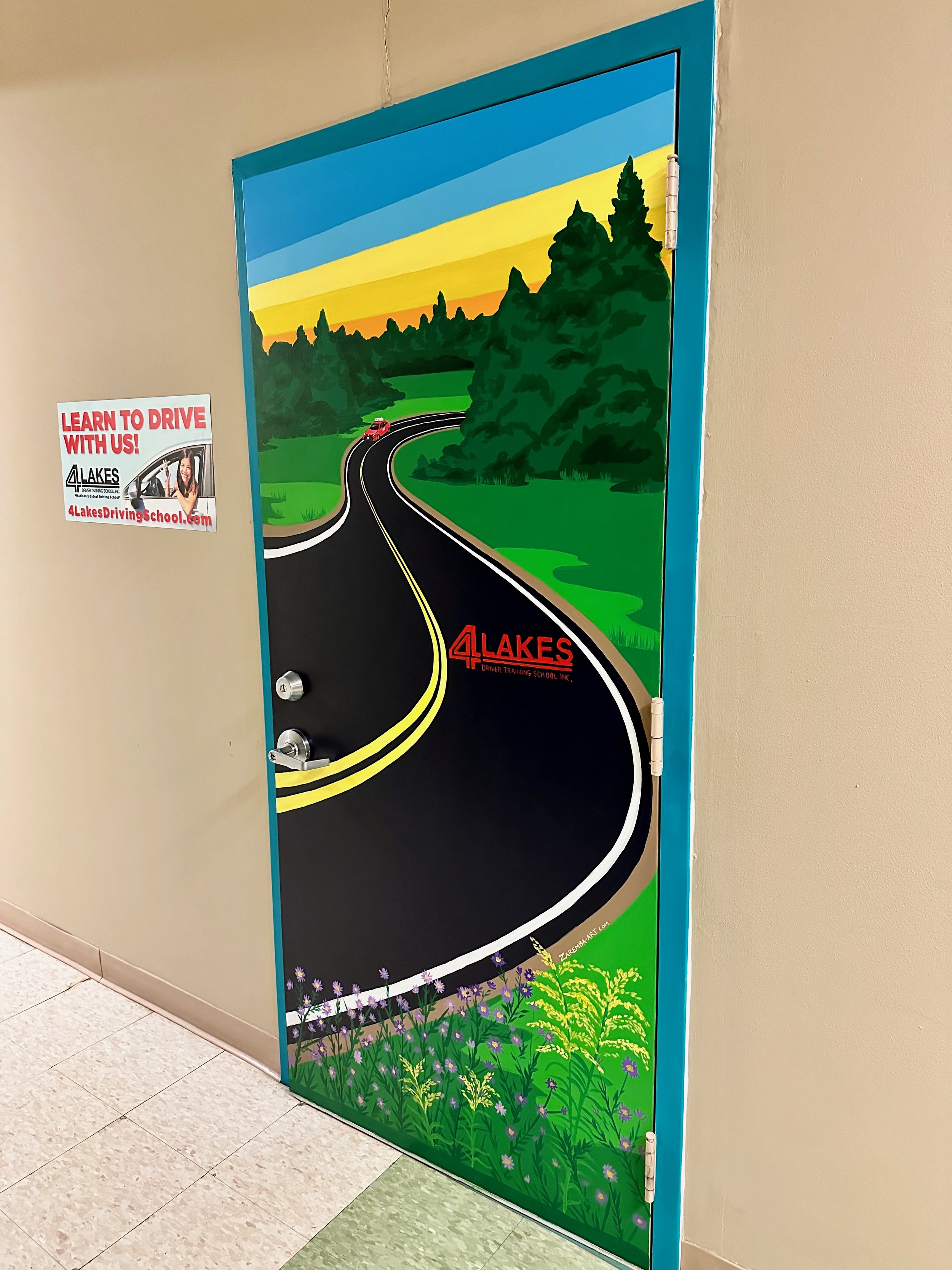 Decorated door with a painted nature scene featuring a winding road, trees, and a sunset or sunrise sky, with the text '4 Lakes' and a logo.