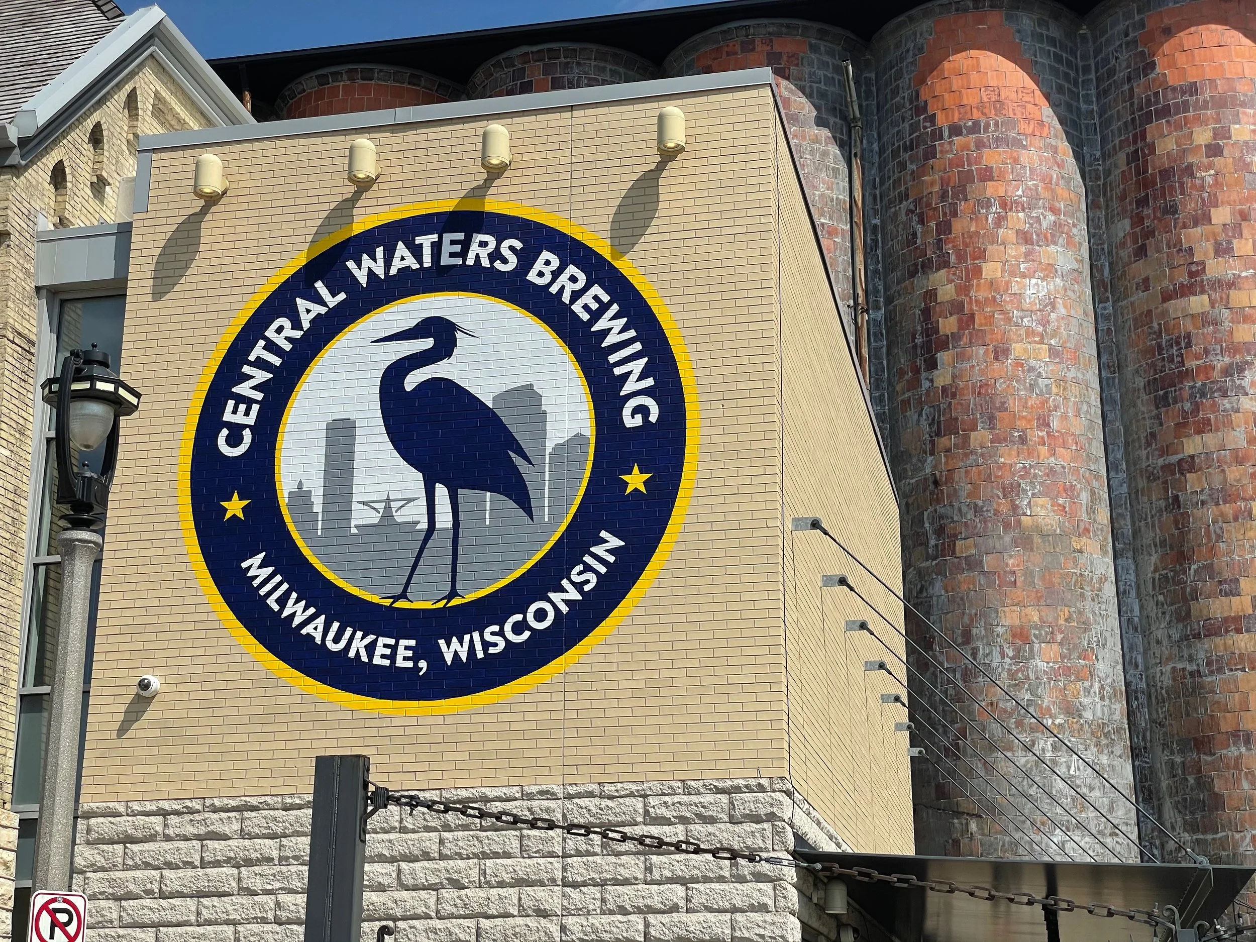 Sign for Central Waters Brewing in Milwaukee, Wisconsin, with a large logo featuring a heron and a city skyline background.