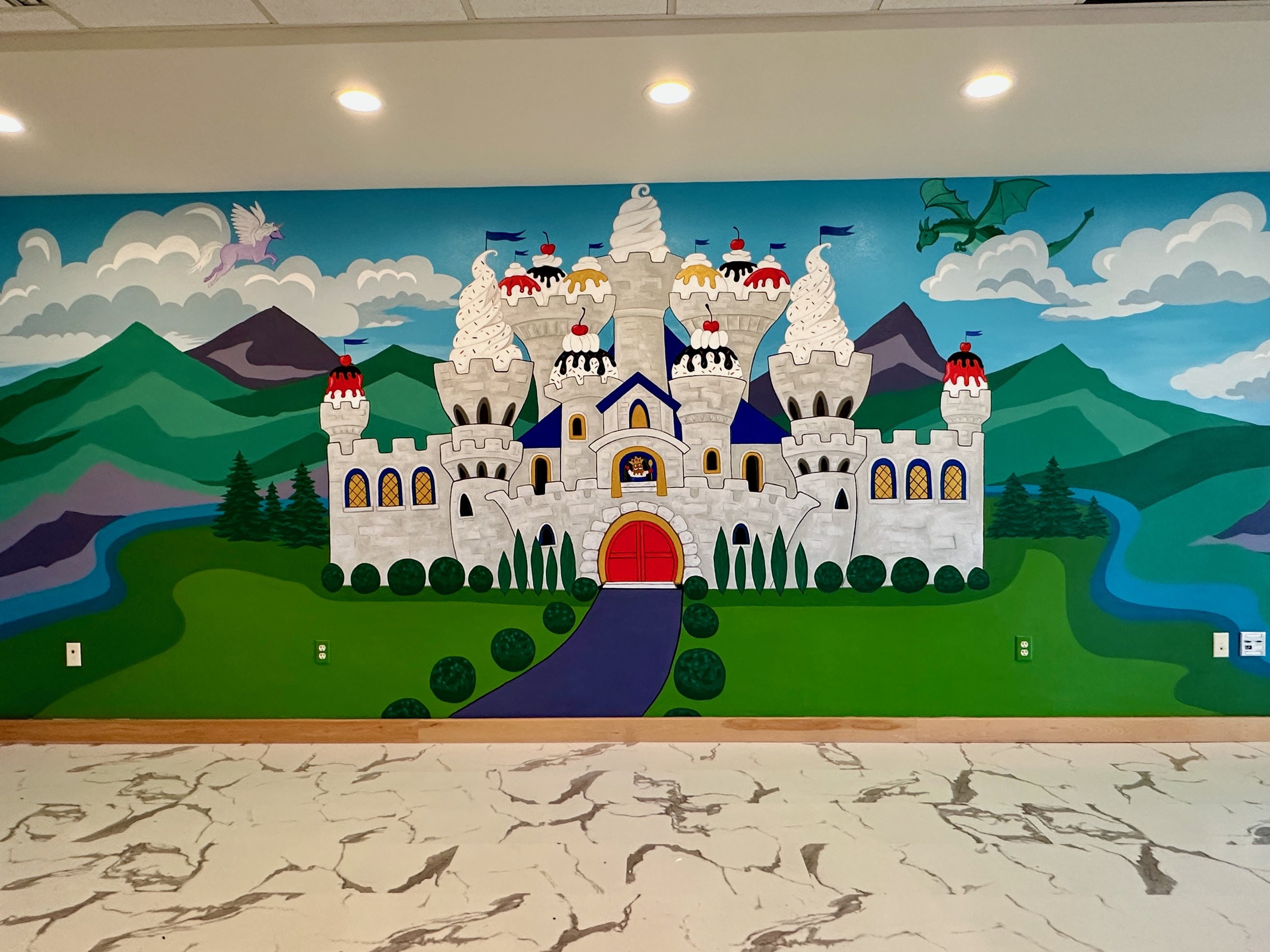 Colorful mural of a castle with towers and turrets, surrounded by green hills, mountains, river, and clouds, with a dragon and a flying unicorn in the sky.