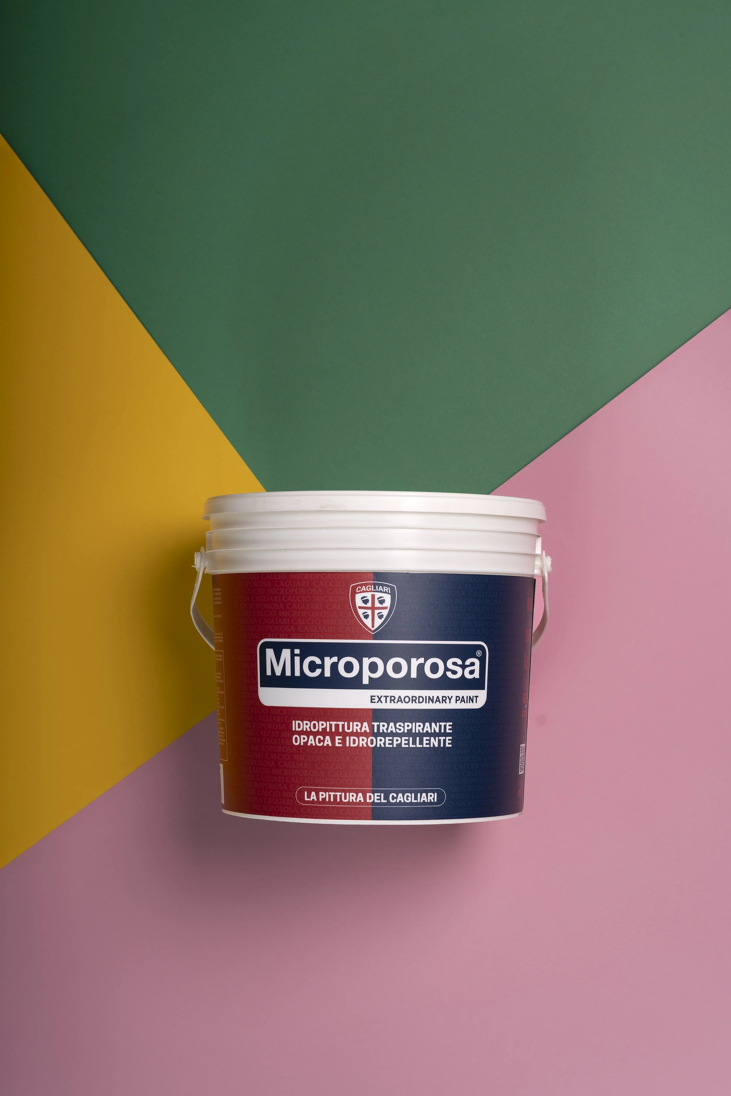 Barattolo di vernice Microporosa con etichetta rossa e blu davanti a uno sfondo di blocchi di colore rosa, verde, giallo e viola.