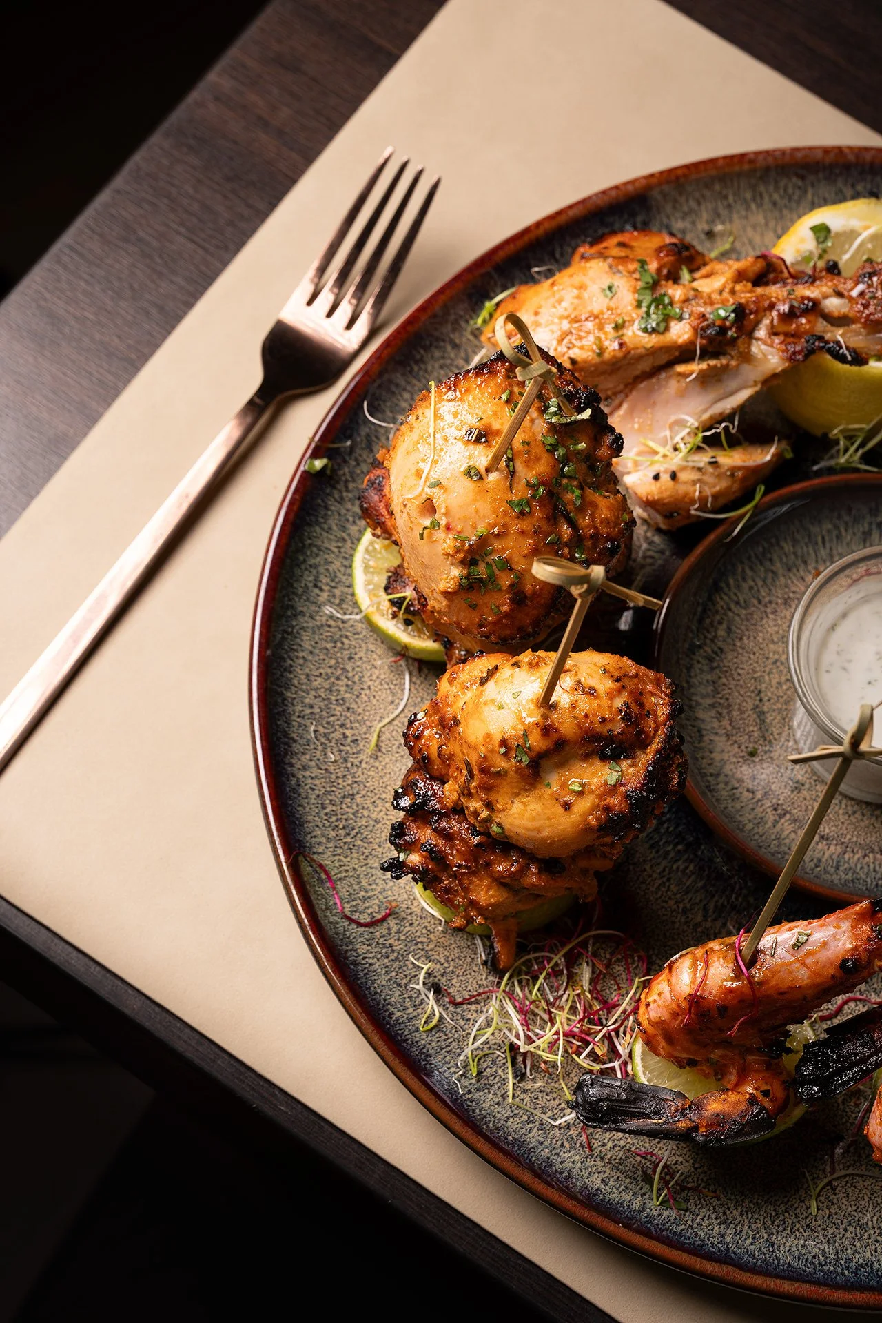 Piatto di pollo grigliato con limone e microgreens, servito su un piatto di ceramica, con una forchetta appoggiata sul lato sinistro.