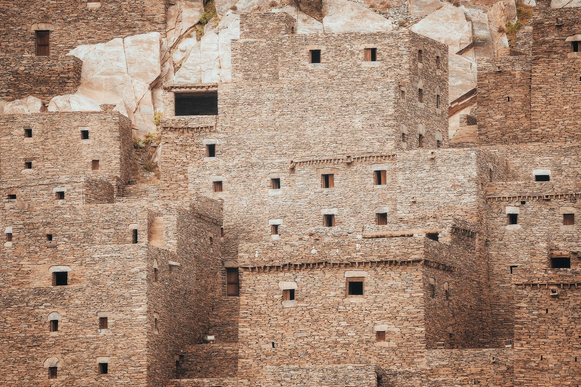 Edificio in pietra con numerose piccole finestre, costruito su una parete rocciosa.