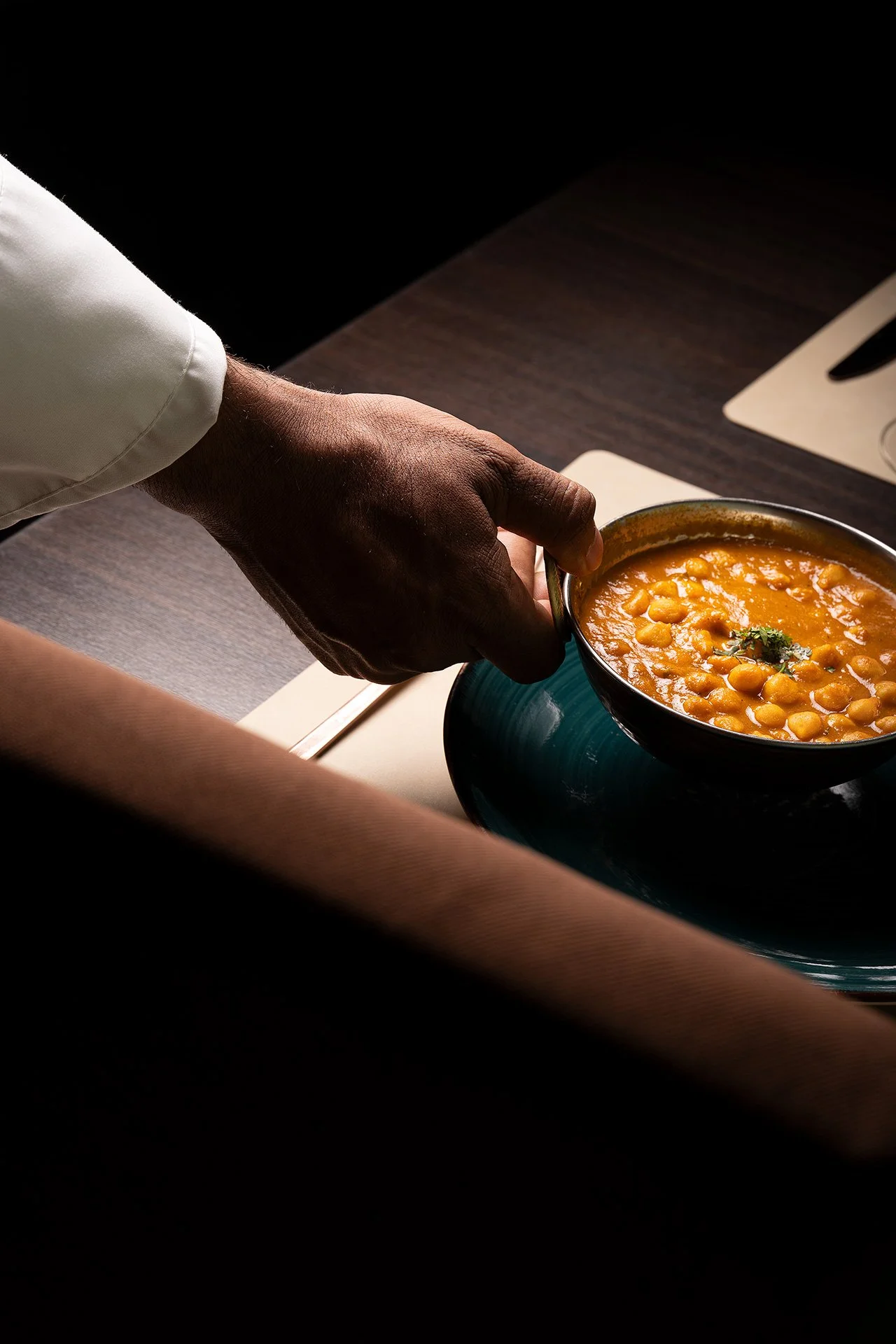 Un piatto di zuppa di ceci in una ciotola nera, con odore aromatico e decorazioni di coriandolo.