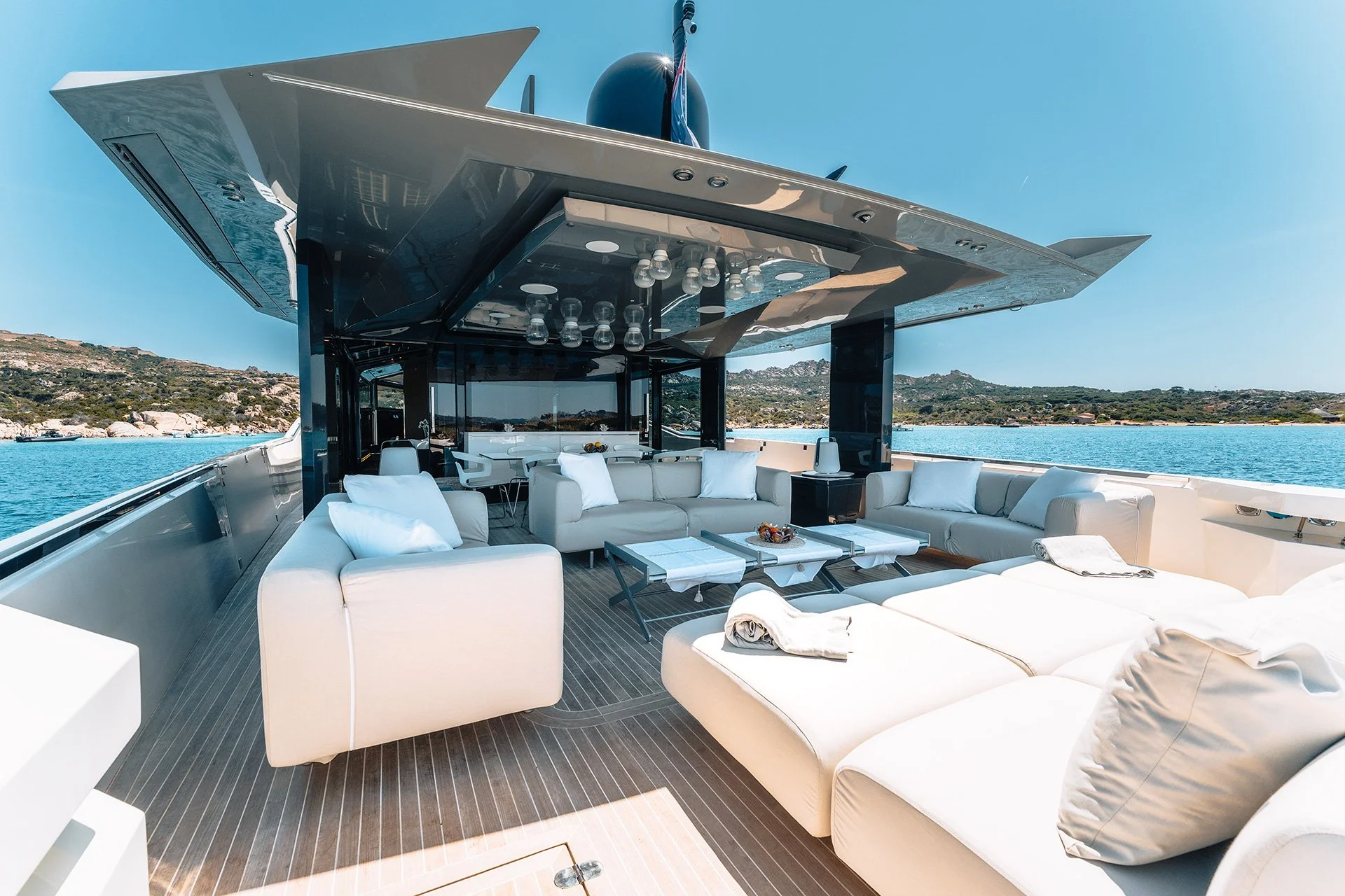 Lusso di uno yacht con divani bianchi, tavolini e illuminazione moderna, vista sul mare e paesaggi costieri.