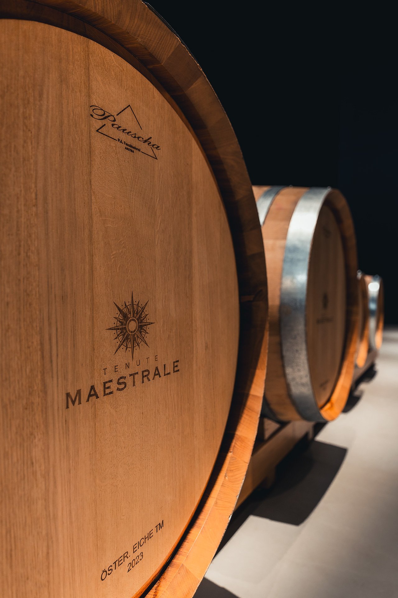 File di botti di vino in botte di legno con tappo di metallo, etichetta del vino Tenute Maestrale.
