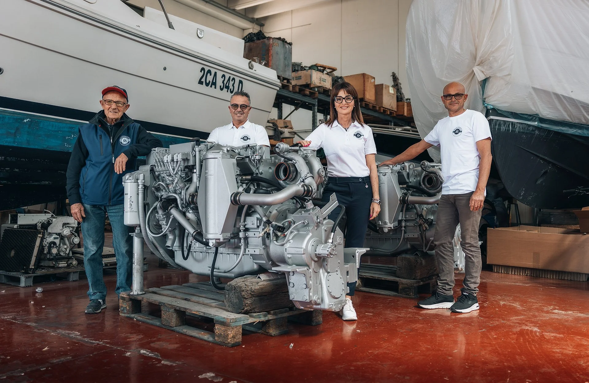 Quattro persone in un'officina meccanica vicino a un motore marino.