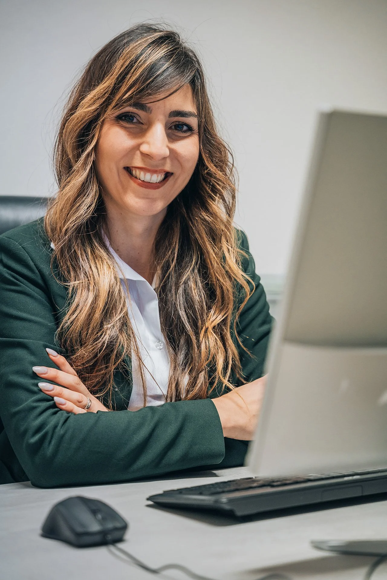 Una donna sorridente seduta davanti a un computer in un ambiente d'ufficio.