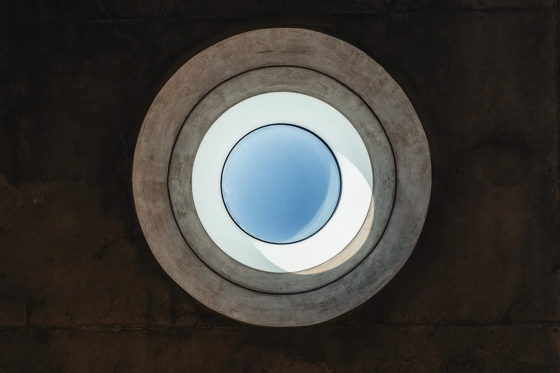 Foto di un foro circolare nel soffitto di un edificio, con visuale verso il cielo azzurro.