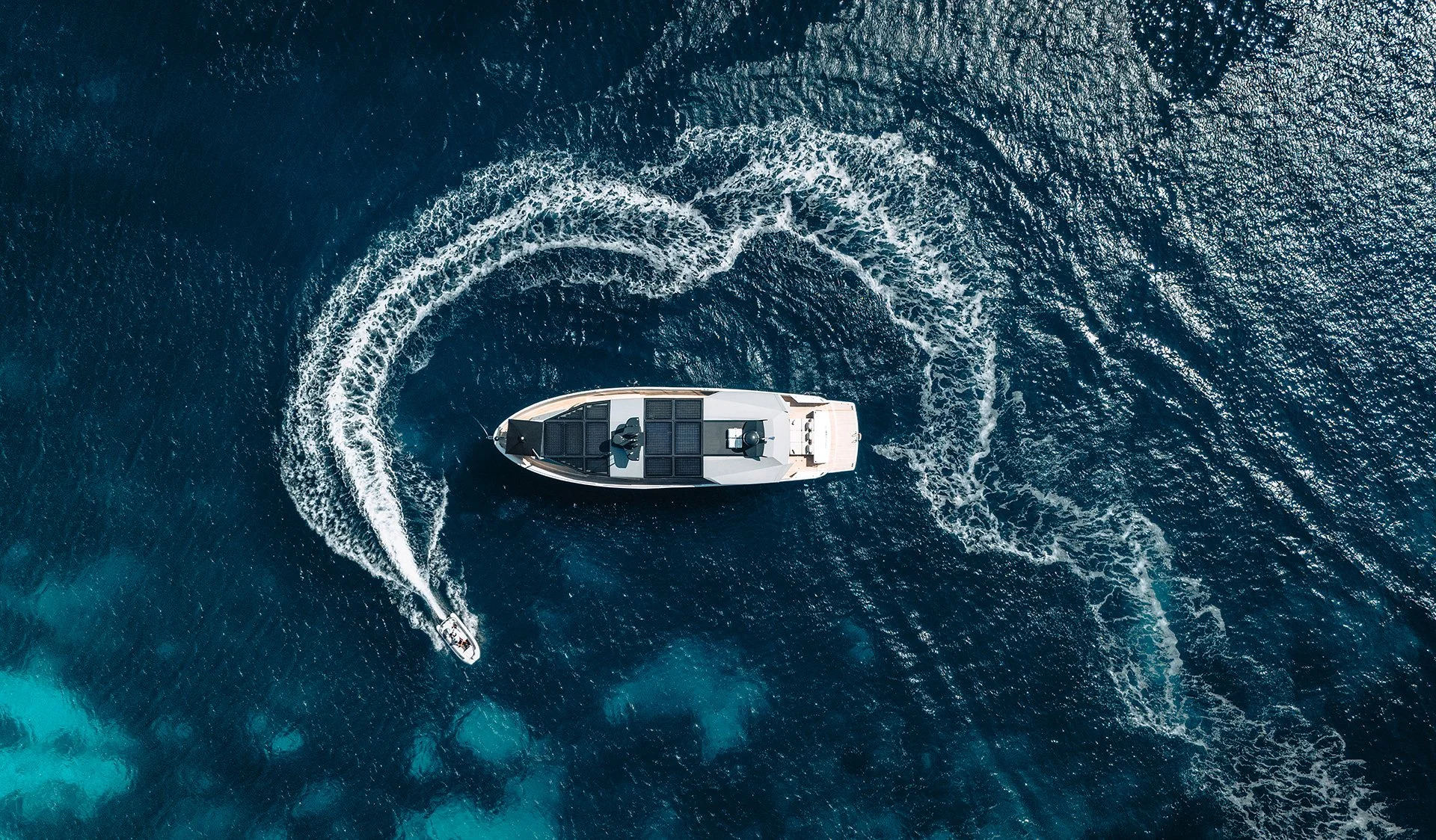 Veduta aerea di una grande barca a motore e una barca più piccola che navigano in mare aperto.