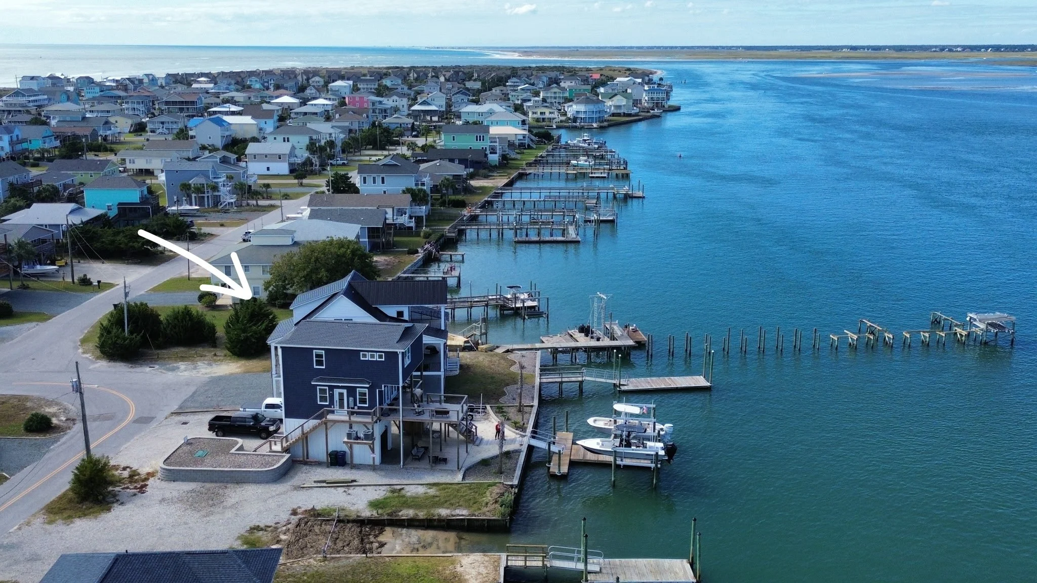 Aerial view of a coastal neighborhood with houses, docks, and boats along the water.