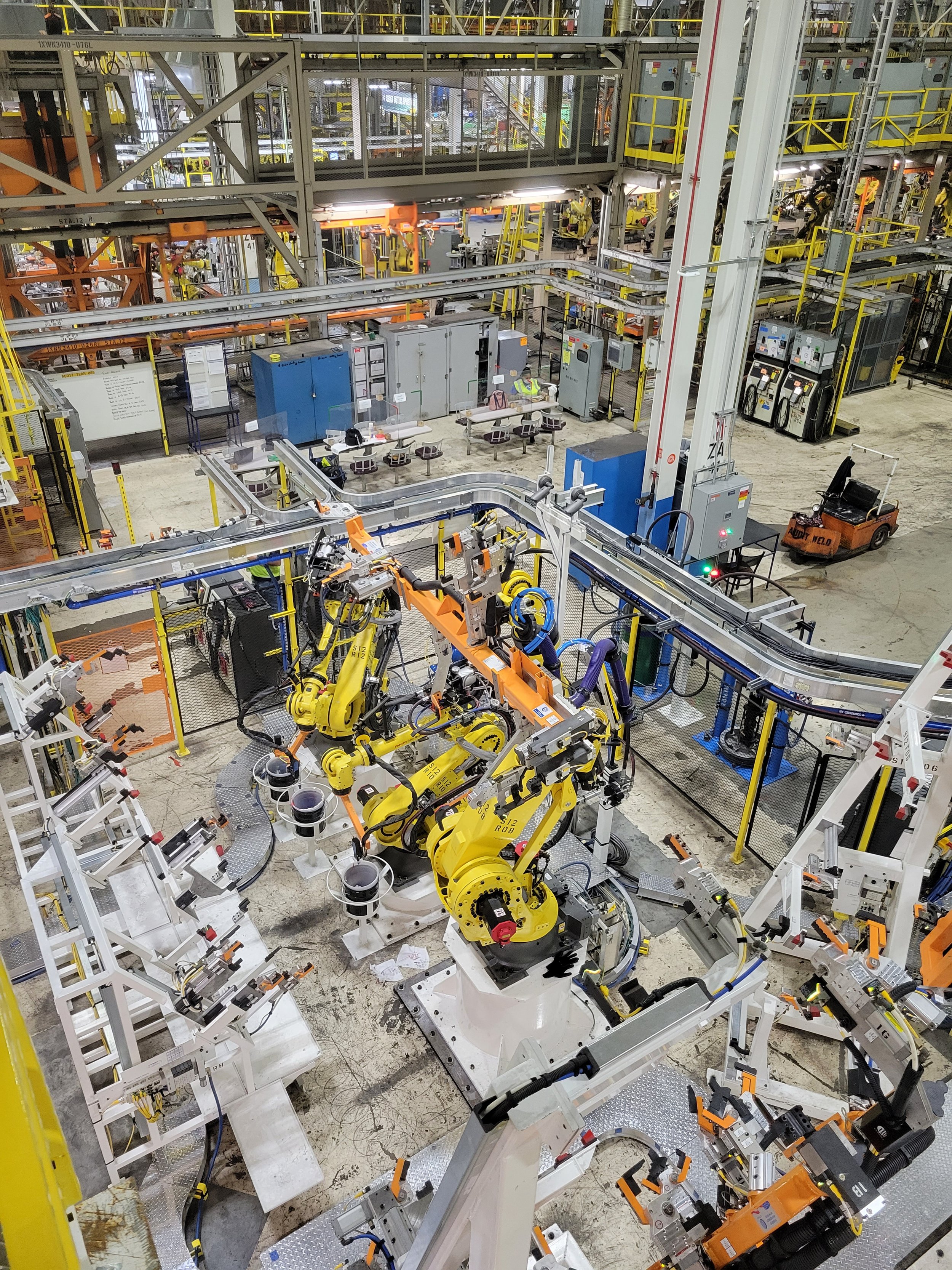 Industrial factory with robotic arms assembling products on a conveyor belt system.