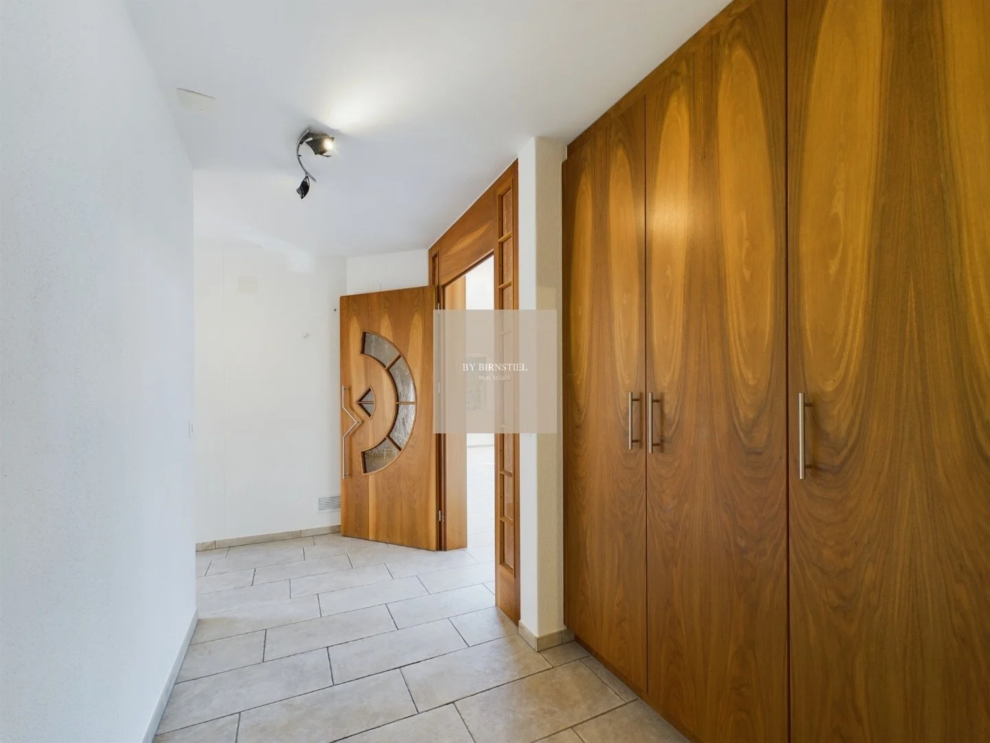 Heller Eingangsbereich mit massgefertigten Einbauschränken aus Holz für maximalen Stauraum.