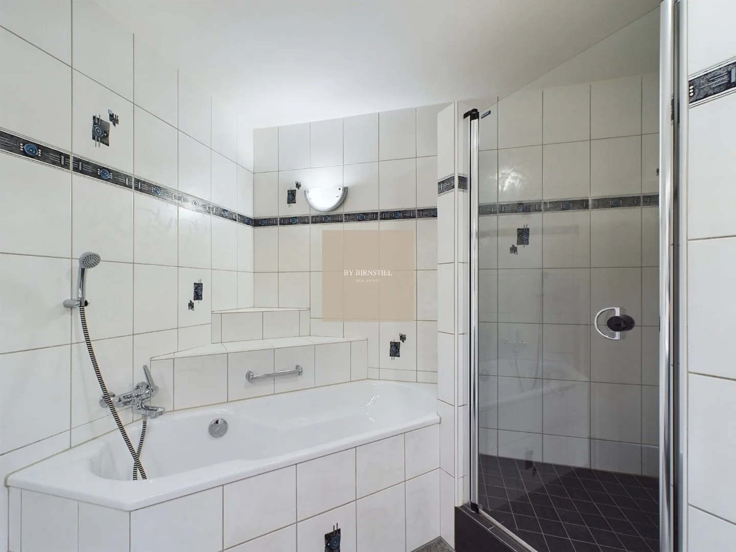 Badezimmer mit Badewanne, separater Dusche und hellen Steinplatten.