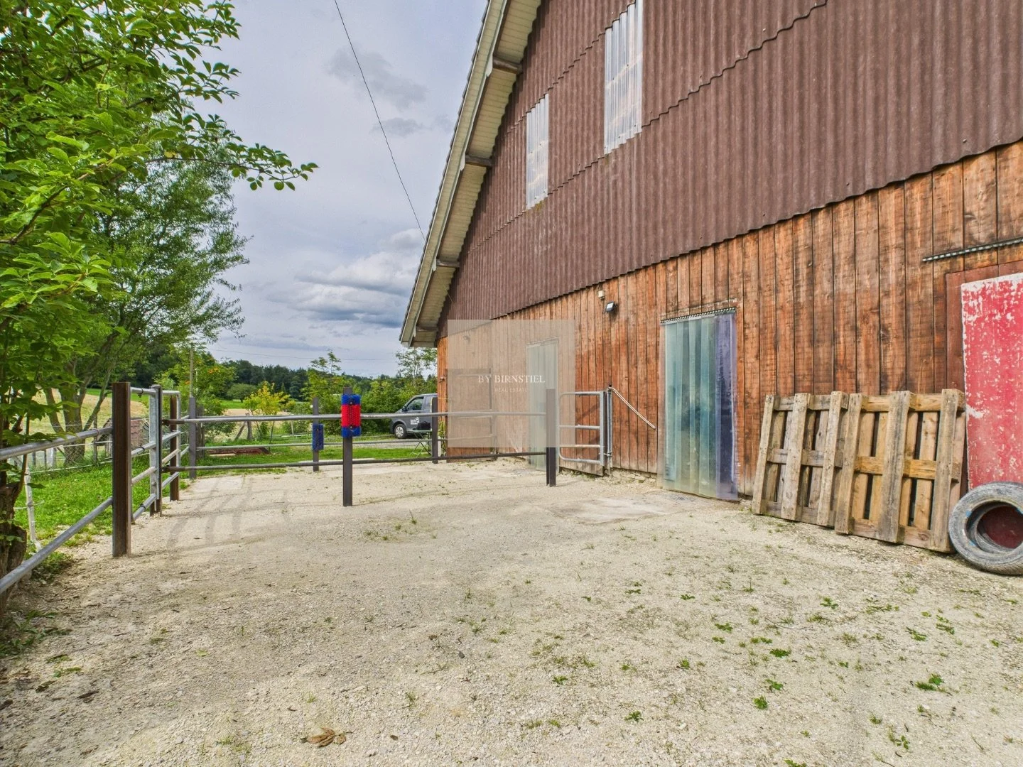 Das Stallgebäude von aussen mit Sattelkammer und angrenzender Weide.