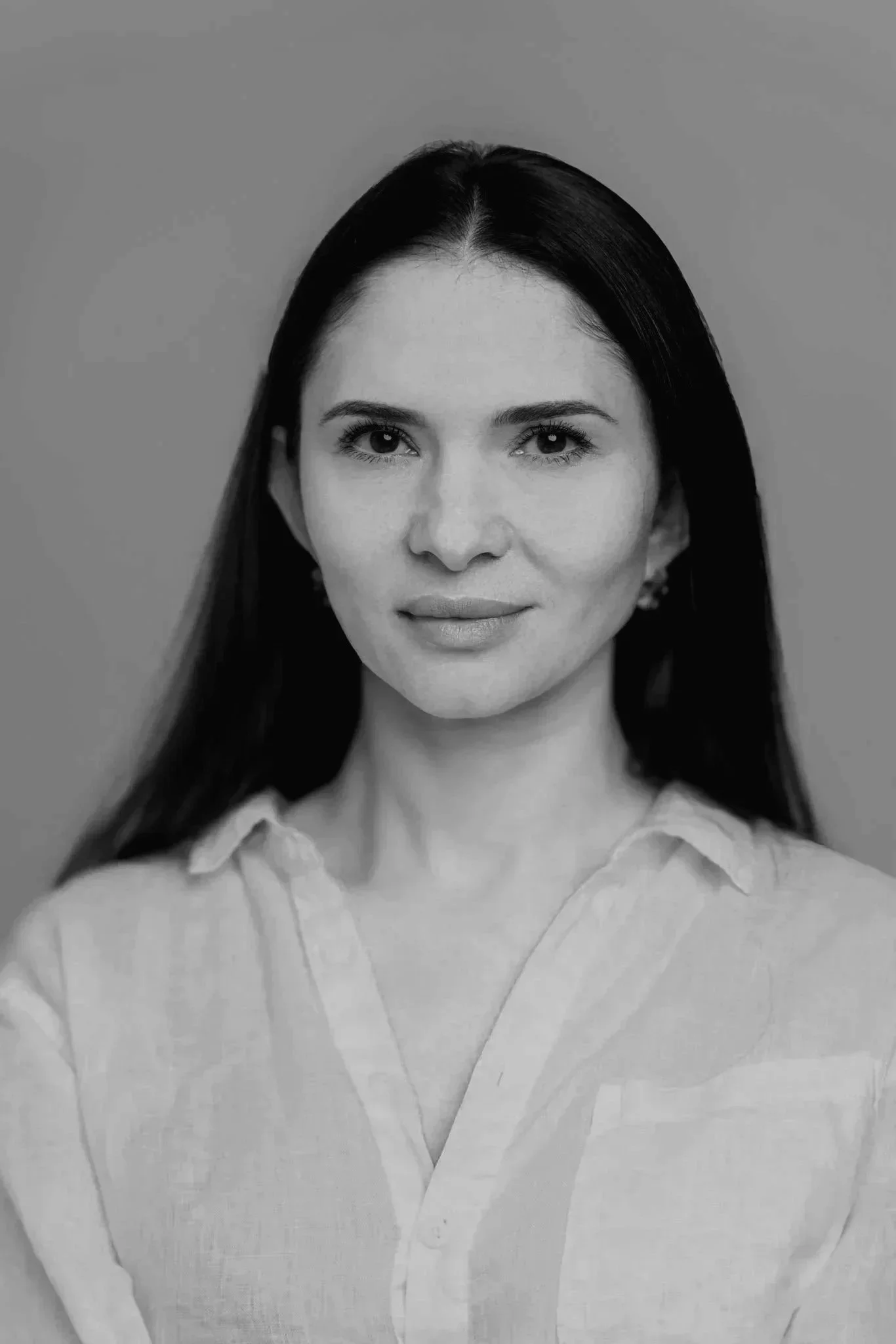 Black and white photo of a smiling man outdoors with trees in the background.