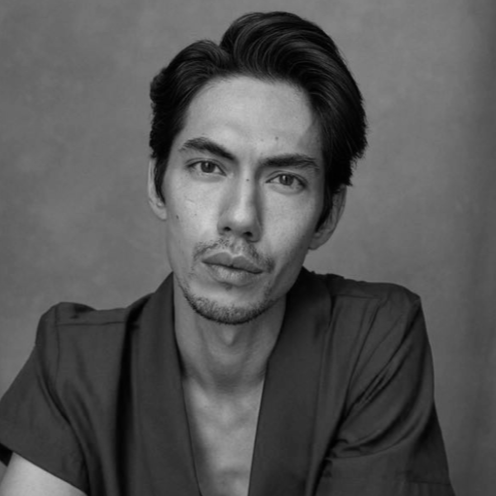 Black and white portrait of a young man with short dark hair, slight facial hair, wearing a dark shirt, looking directly at the camera with a serious expression.