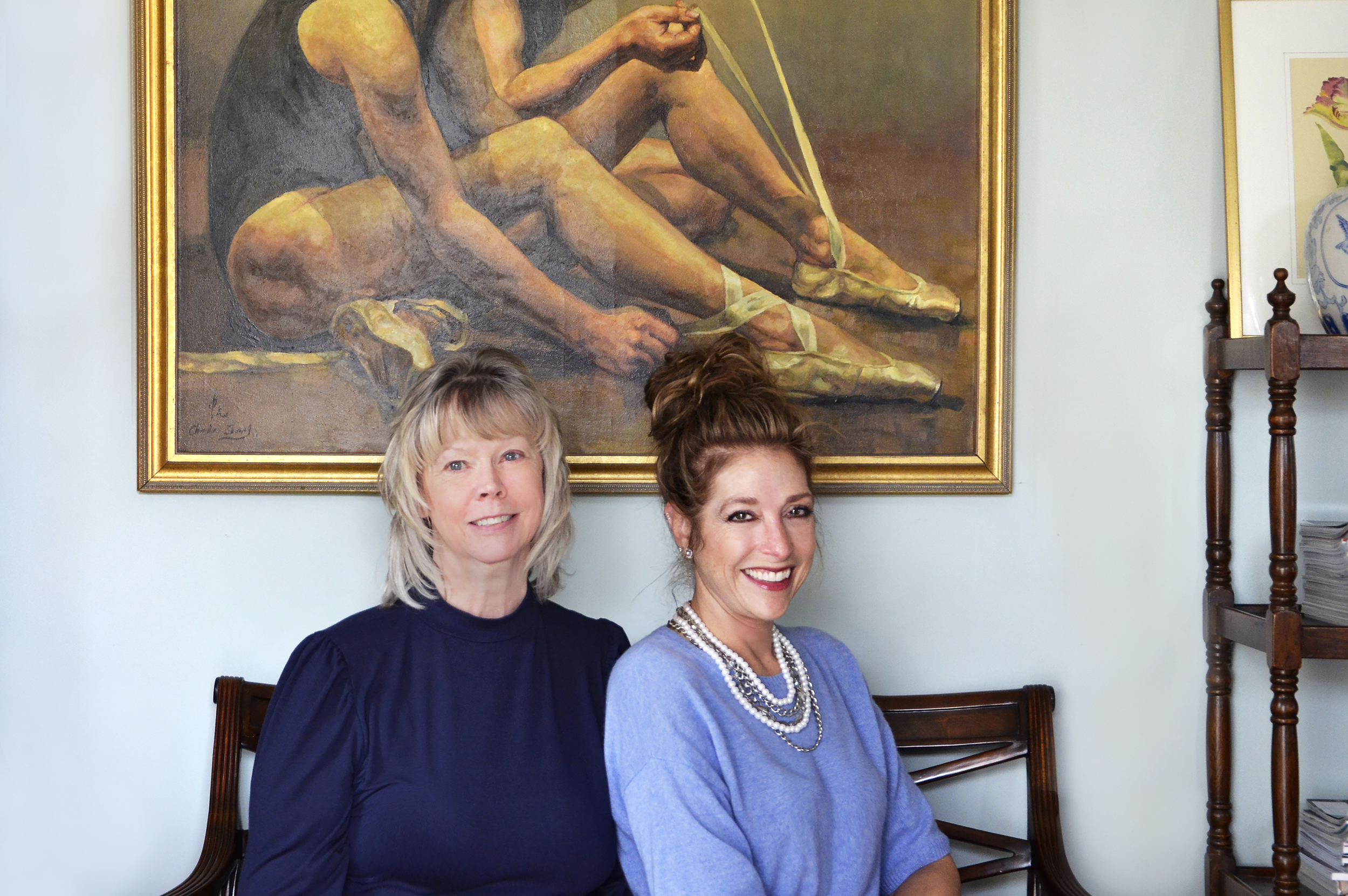 Kim and Debbie, seated in front of dancer painting in gold frame