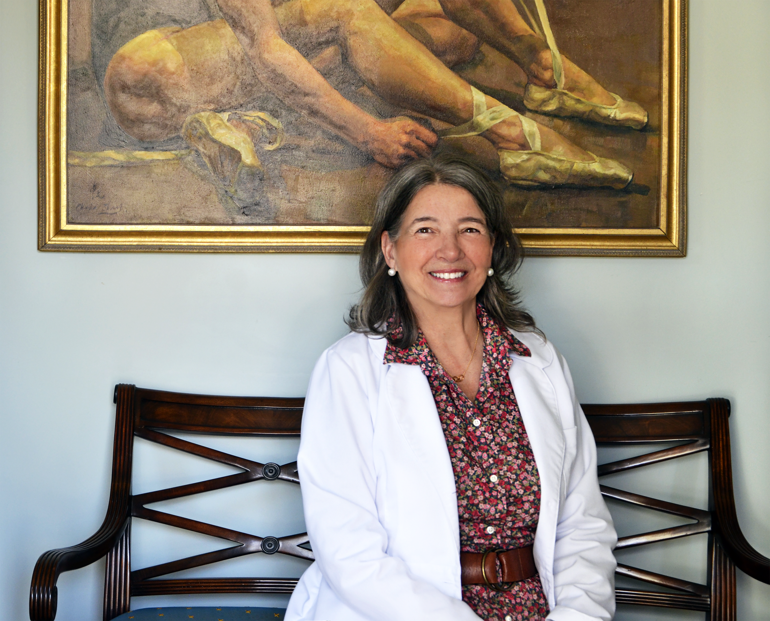 image of Dr Sally Vail seated with ballet dancer painting in background