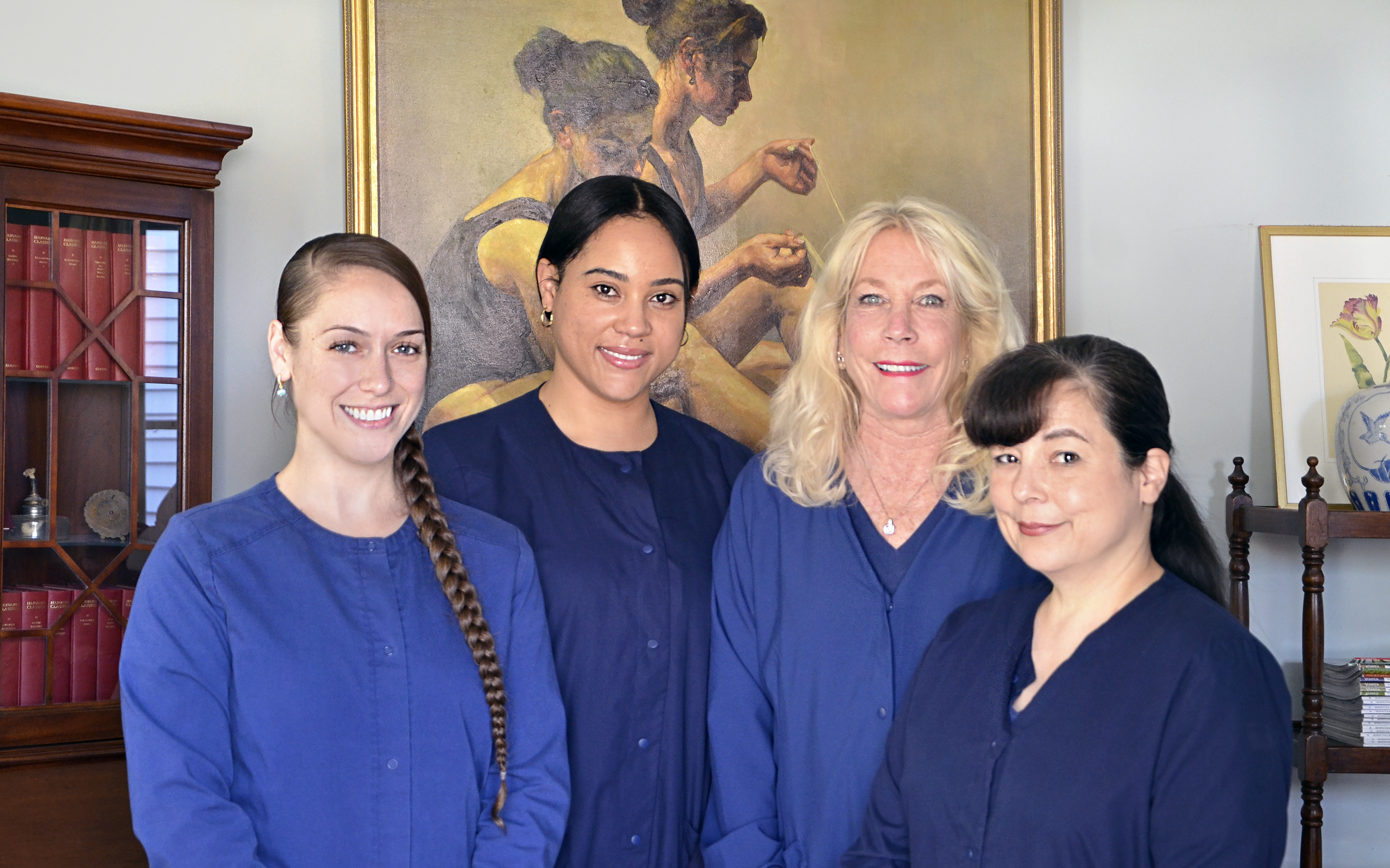 Jessica, Nina, Candace and Shannon in royal blue scrubs standing in front of dancer painting in gold frame