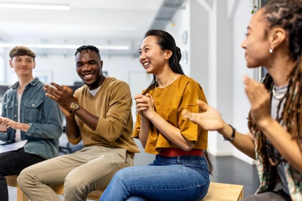 People sitting and laughing in a bright room, engaged in a lively conversation or activity.